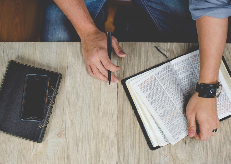 Free Image of Person studying an open Bible on wood table 
