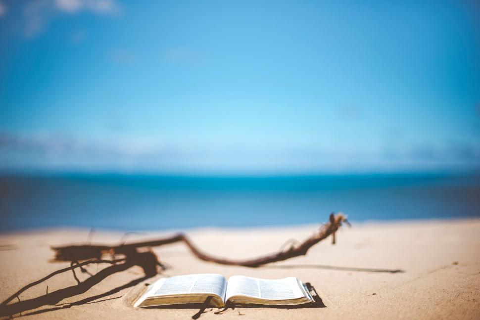 Free Image of Open book on sandy beach with clear sky 