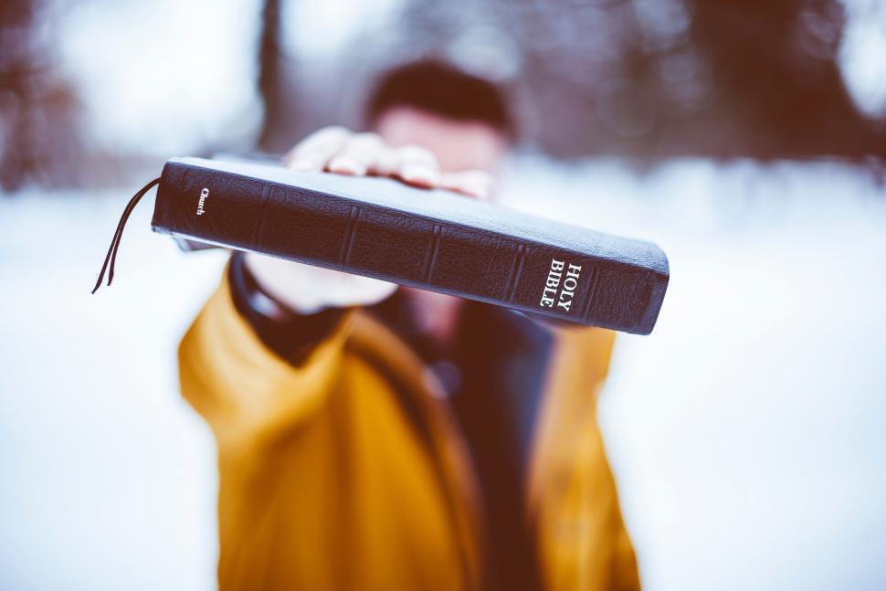 Free Image of Person holding Bible towards camera in snow 