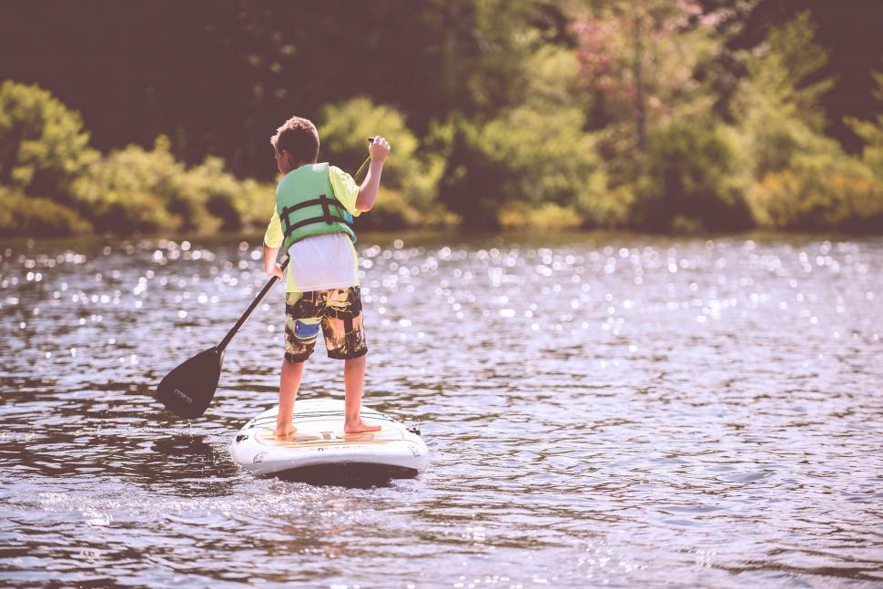 Free Image of Boy paddling on a stand-up paddleboard 