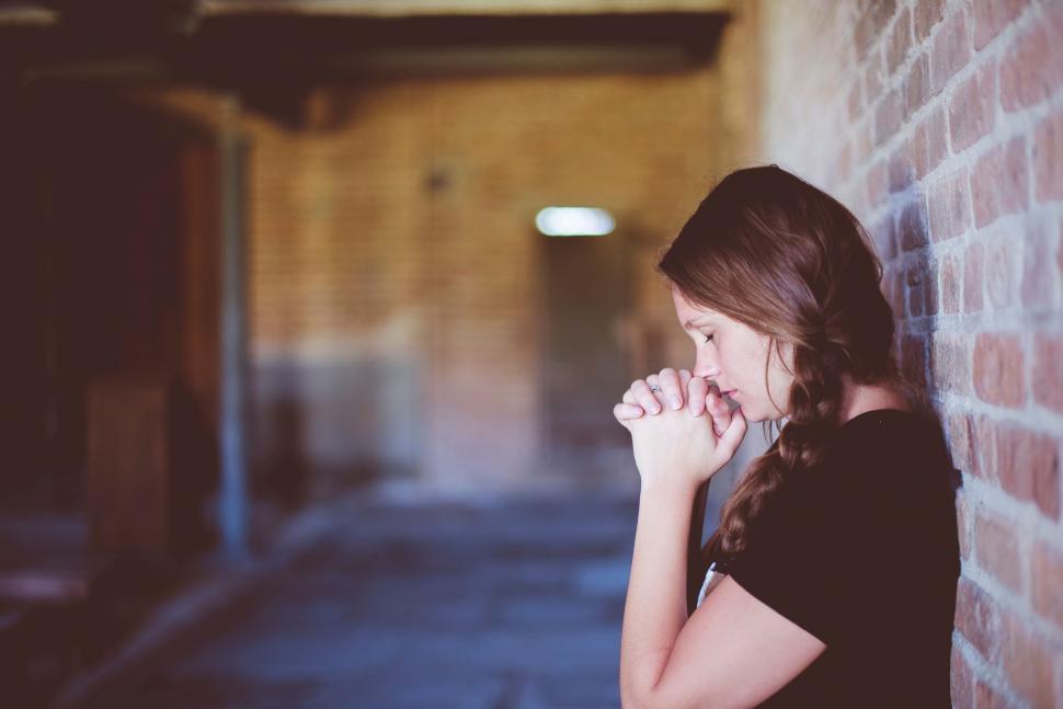 Free Image of Woman leaning against brick wall obscured 