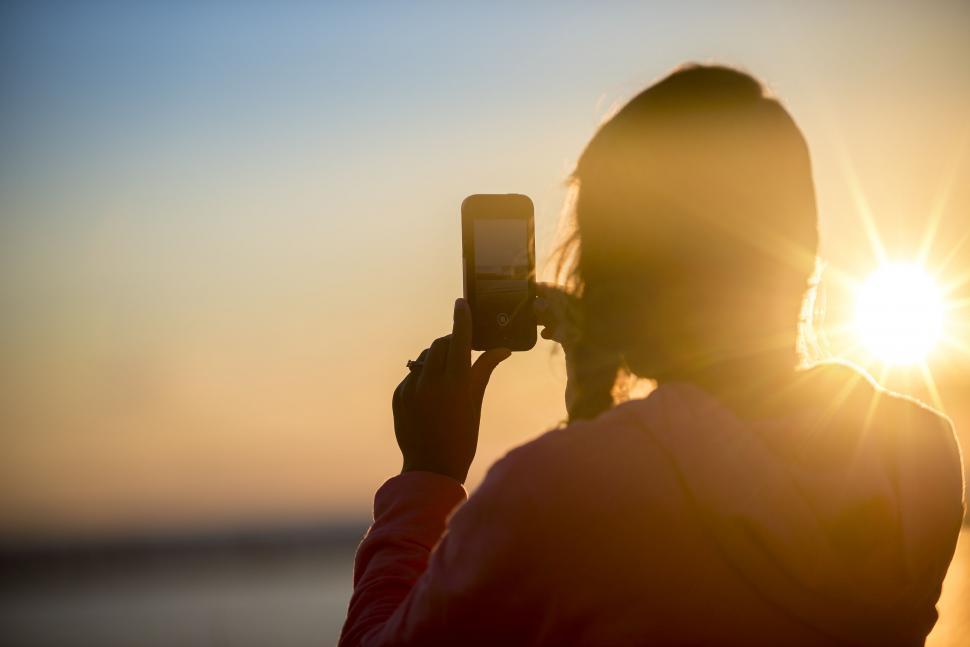 Free Image of Silhouette capturing sunset on phone 