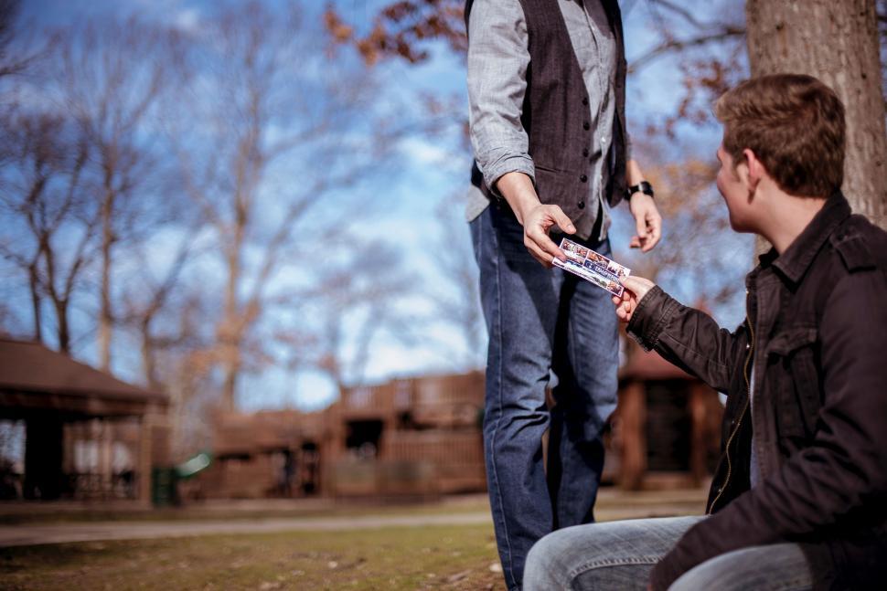 Free Image of Man giving a brochure to another man at the park 