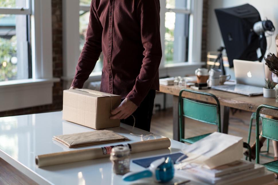 Free Image of Person sealing a package on a table 