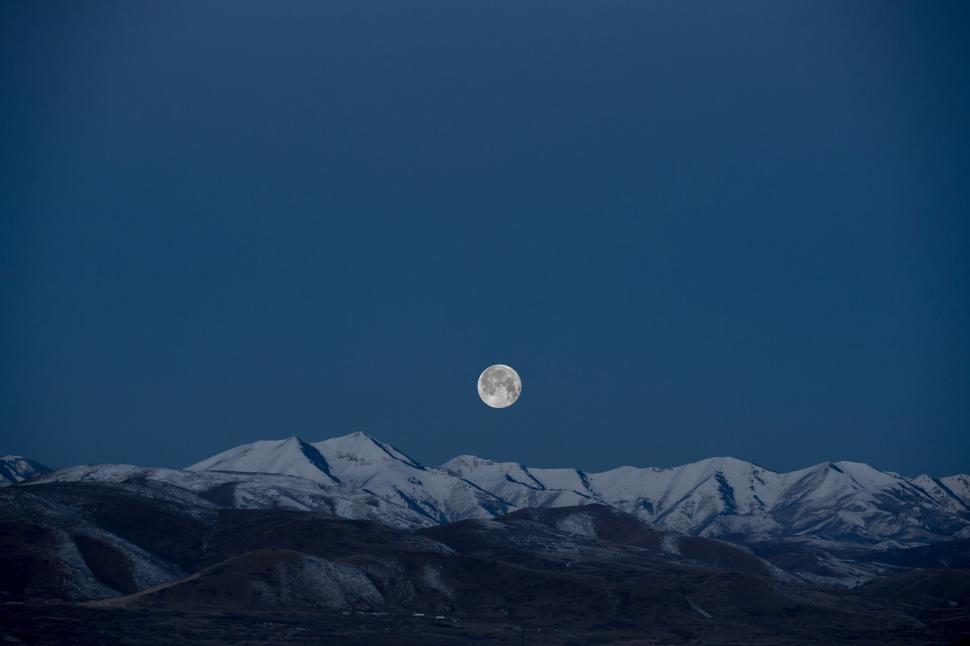 Free Image of Full moon over snow-covered mountains at dusk 