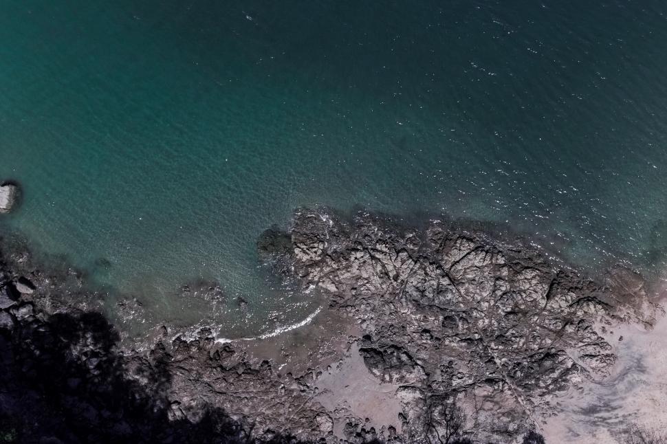 Free Image of Aerial view of rocky coastline and blue sea 