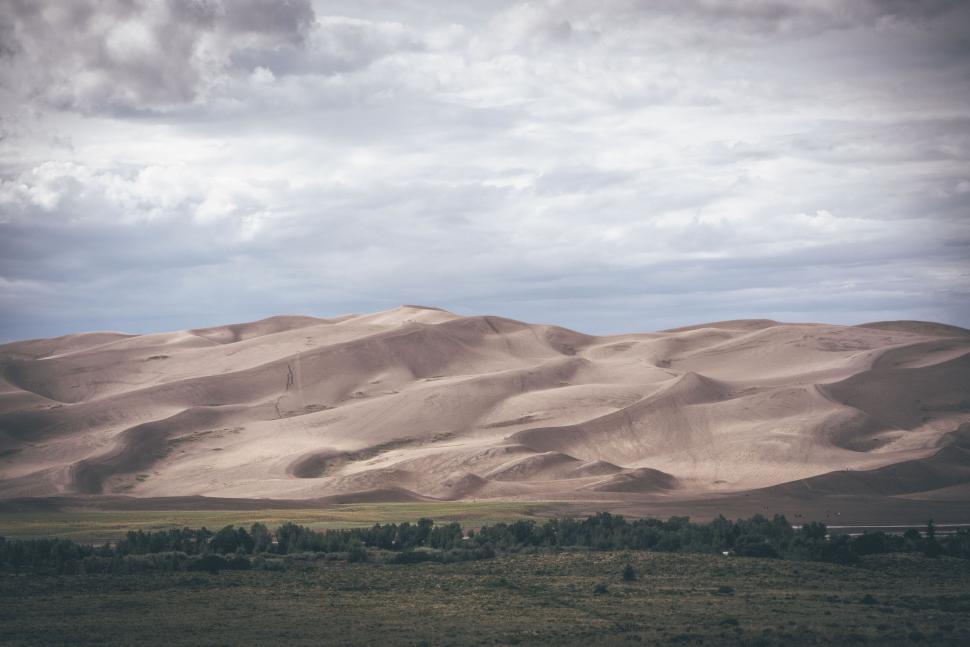 Free Image of Serene sand dunes under a cloudy sky 