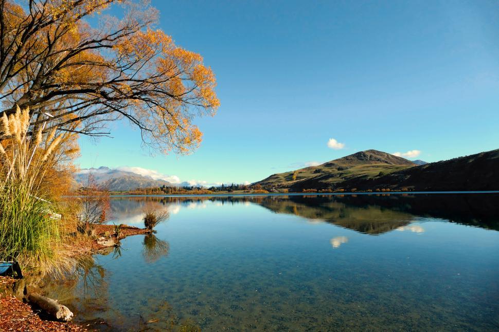 Free Image of Calm lake reflecting the clear blue sky 