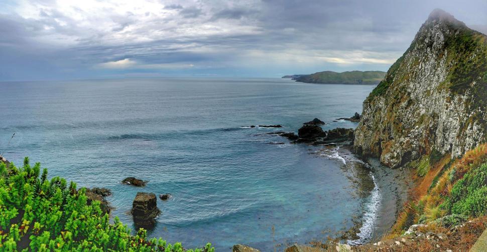 Free Image of Panoramic seascape with rocky shore and foliage 