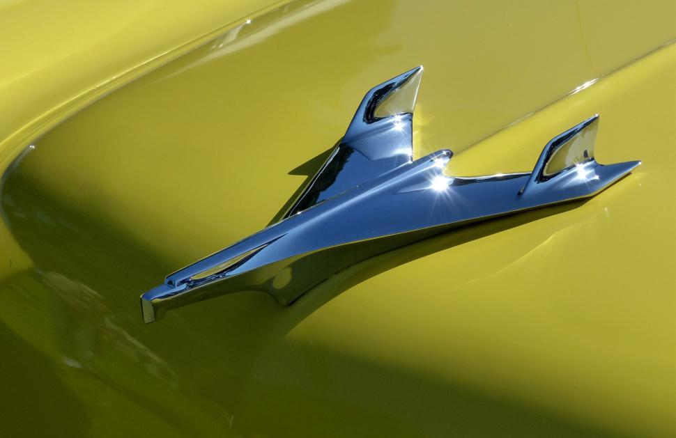 Free Image of Classic car emblem in chrome on yellow paint 