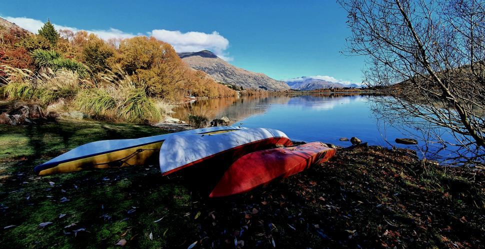 Free Image of Canoes lying beside a calm mountain lake 