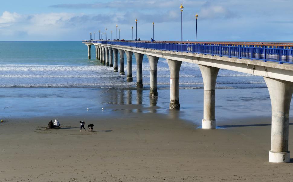 Free Image of Long pier extending into the ocean with people 