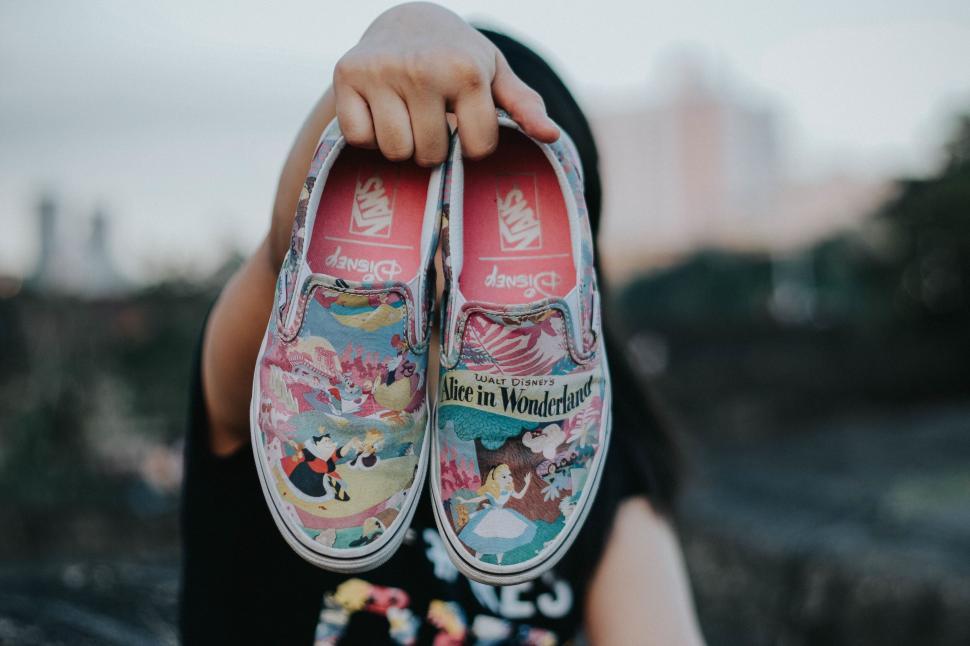 Free Image of Person holding colorful Disney Vans shoes 