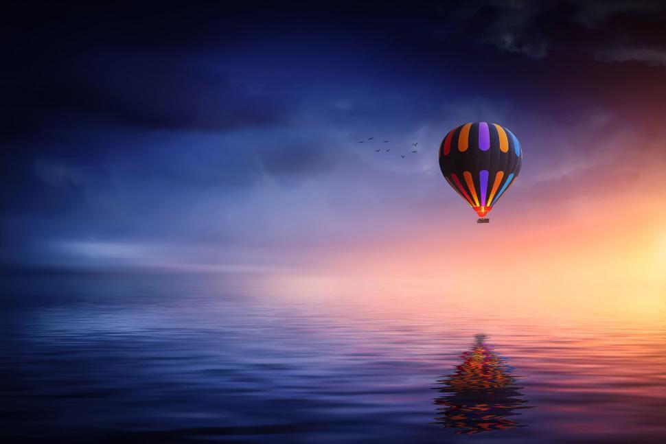 Free Image of Hot air balloon gliding over calm waters 
