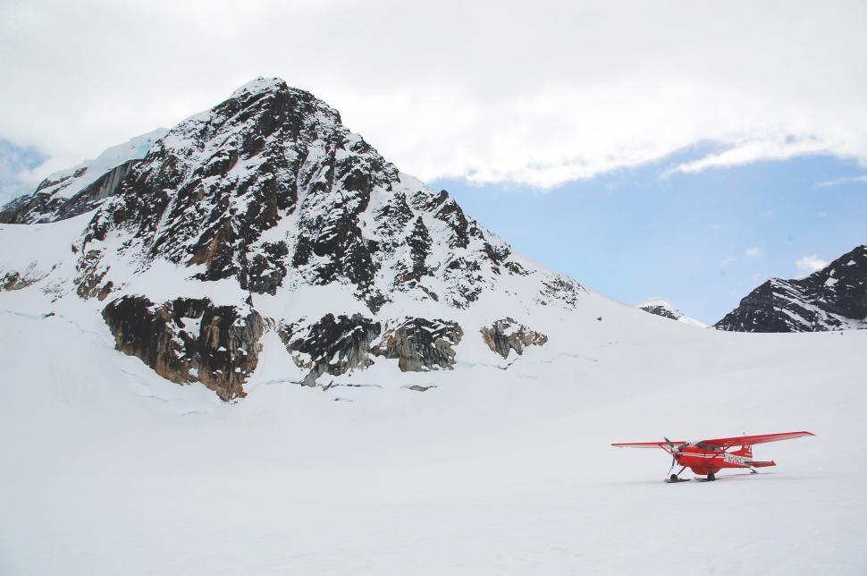 Free Image of Red plane on snowy mountain under blue sky 