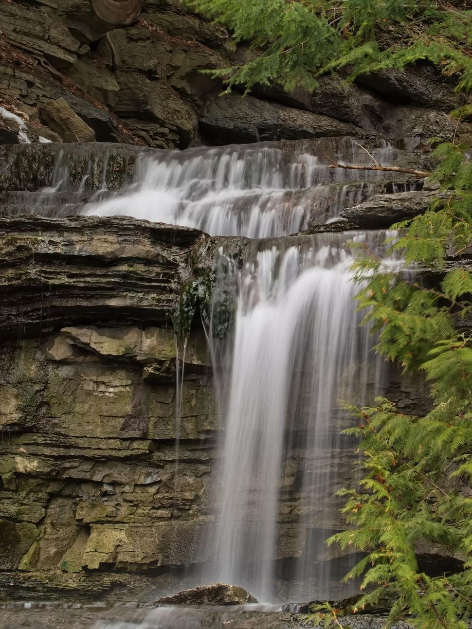 Free Image of Tranquil waterfall cascading down rocky cliff 