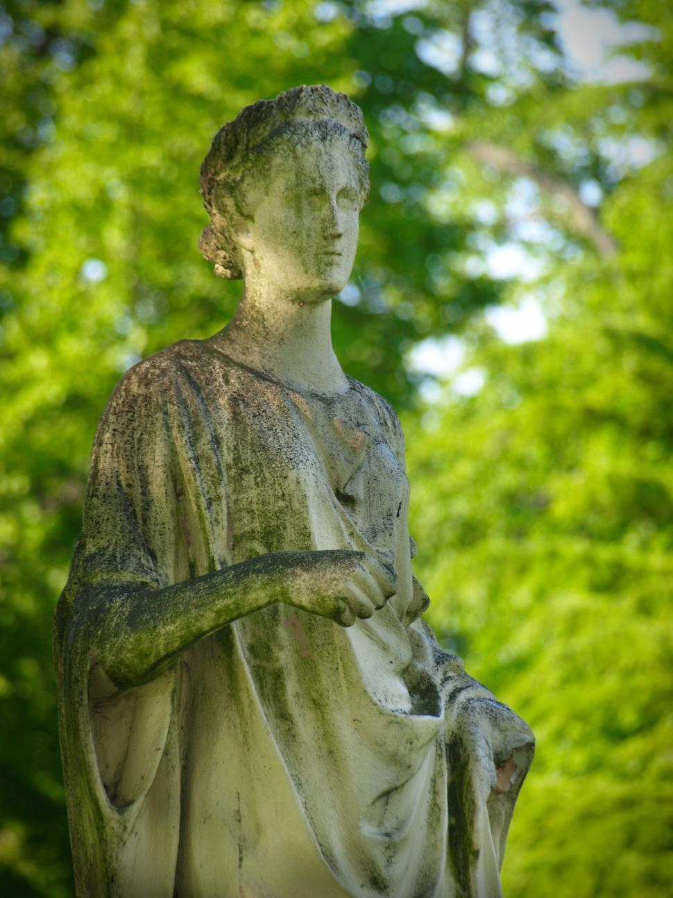 Free Image of Weathered stone statue in lush green park 