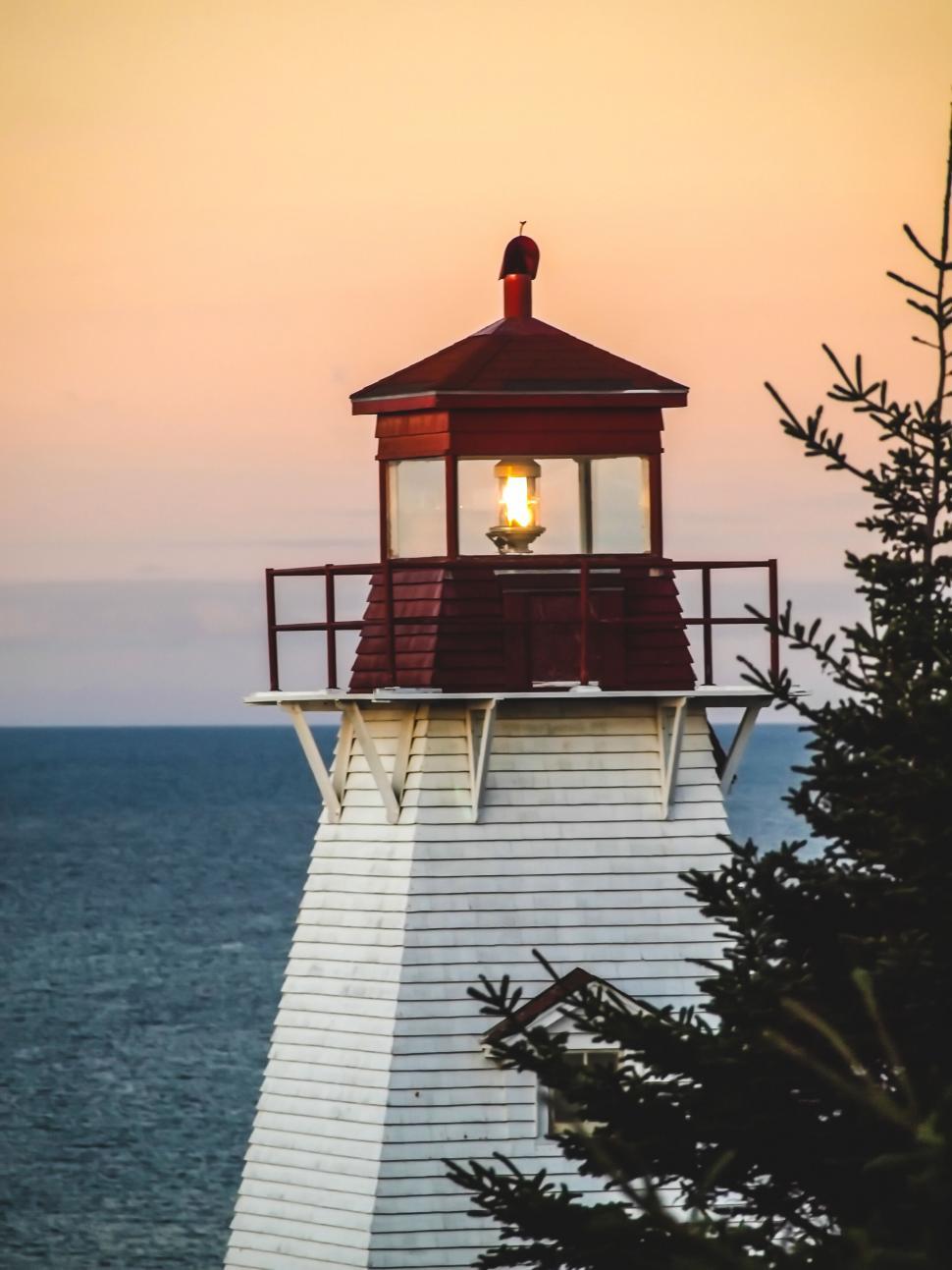 Free Image of Coastal lighthouse at sunset with trees 