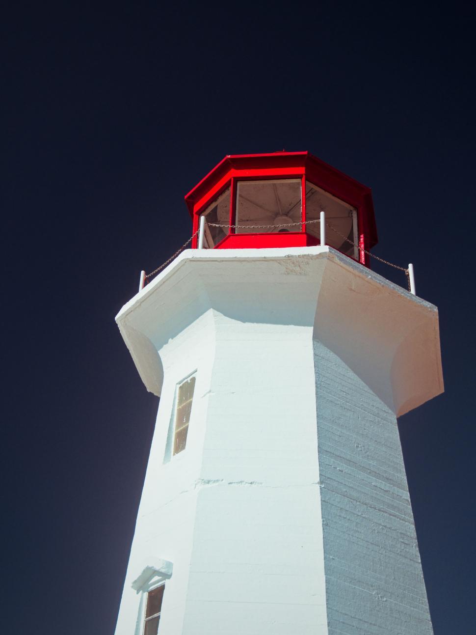 Free Image of White lighthouse with red top against night sky 