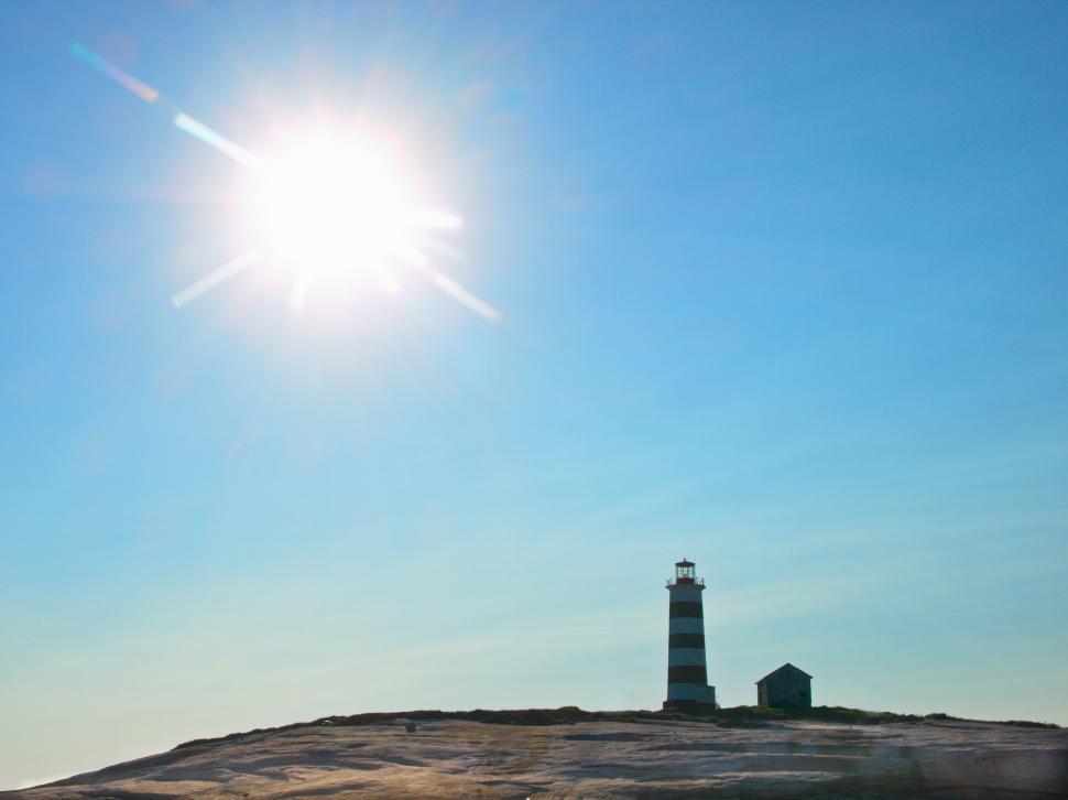 Free Image of Sunny coastal landscape with a striped lighthouse 