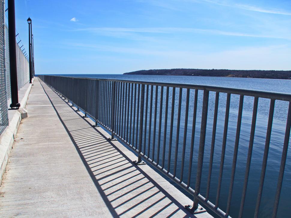 Free Image of Empty lakeside pathway under clear blue sky 