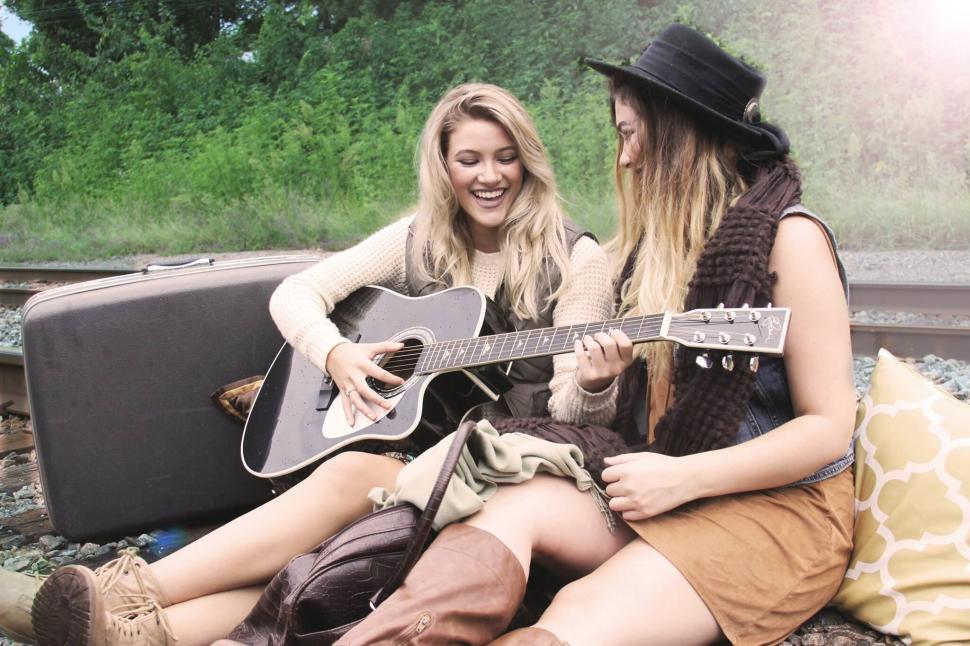 Free Image of Two friends playing guitar on train tracks 
