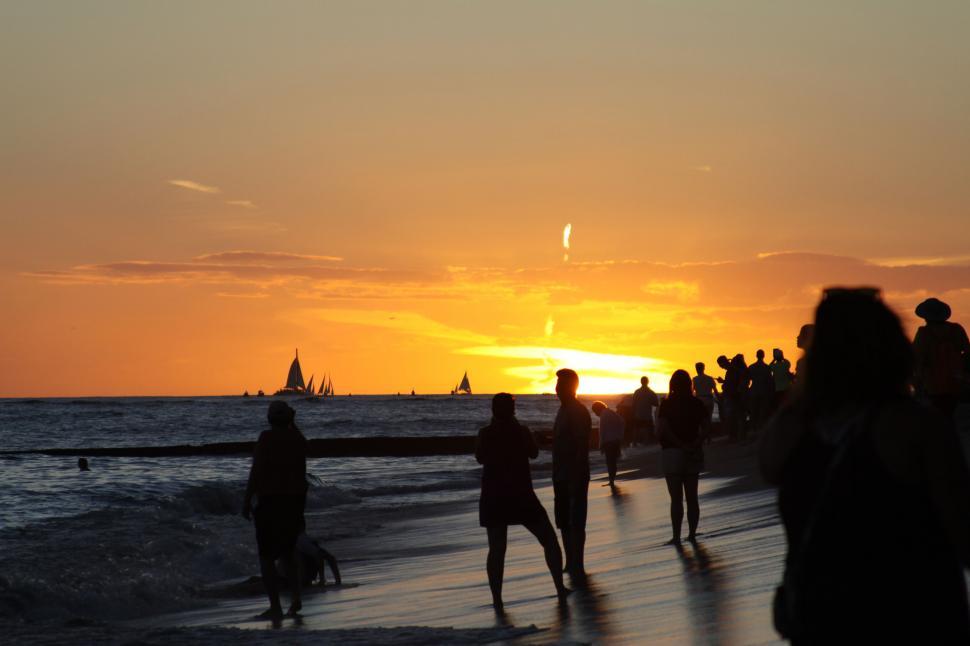 Free Image of Sunset silhouette on the beach with sailors 