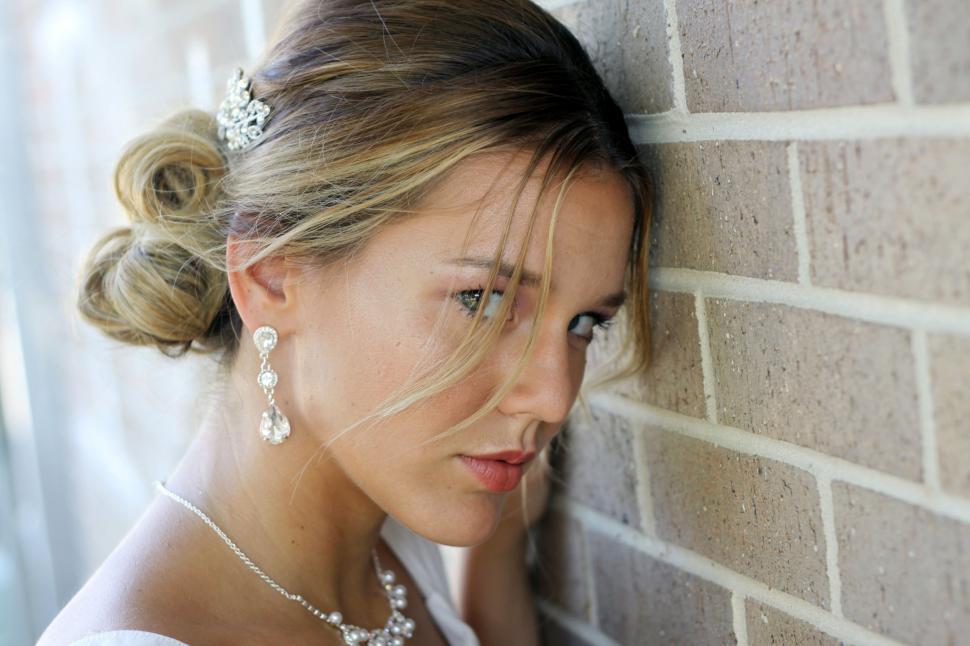 Free Image of Elegant bride leaning on brick wall 