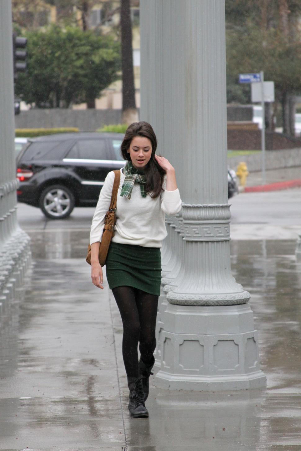 Free Image of Woman walking in rain by classical columns 