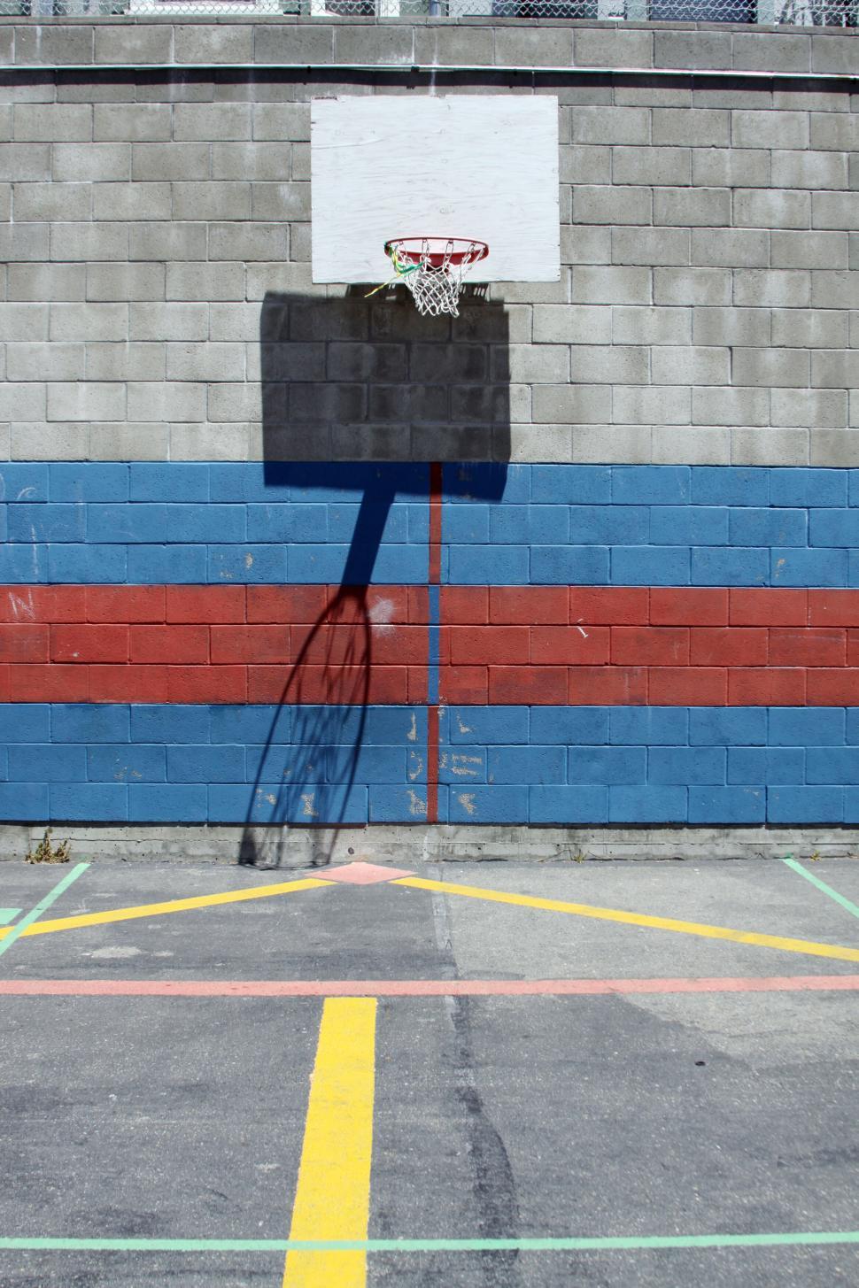 Free Image of Outdoor basketball hoop with shadow on wall 