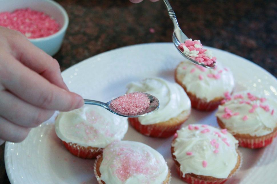 Free Image of Decorating Pink Cupcakes with Sprinkles 