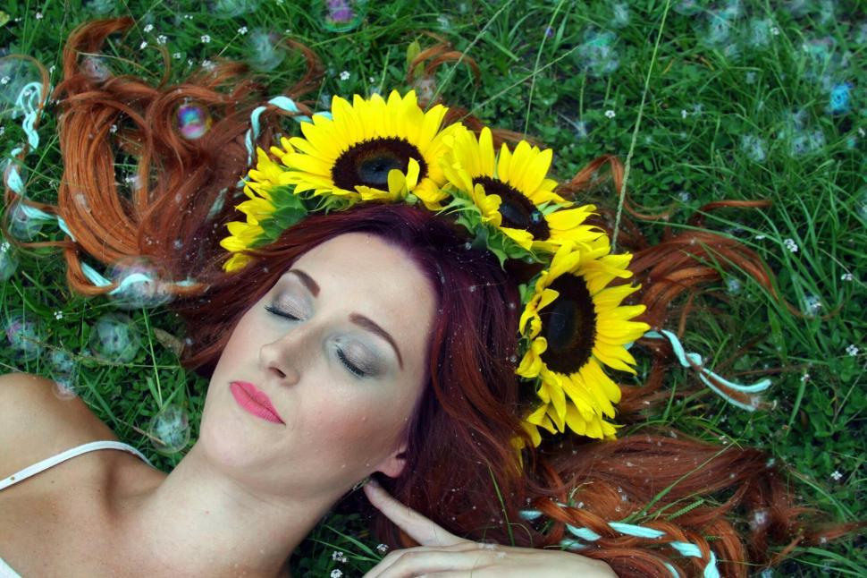 Free Image of Woman lying in grass with sunflowers in hair 