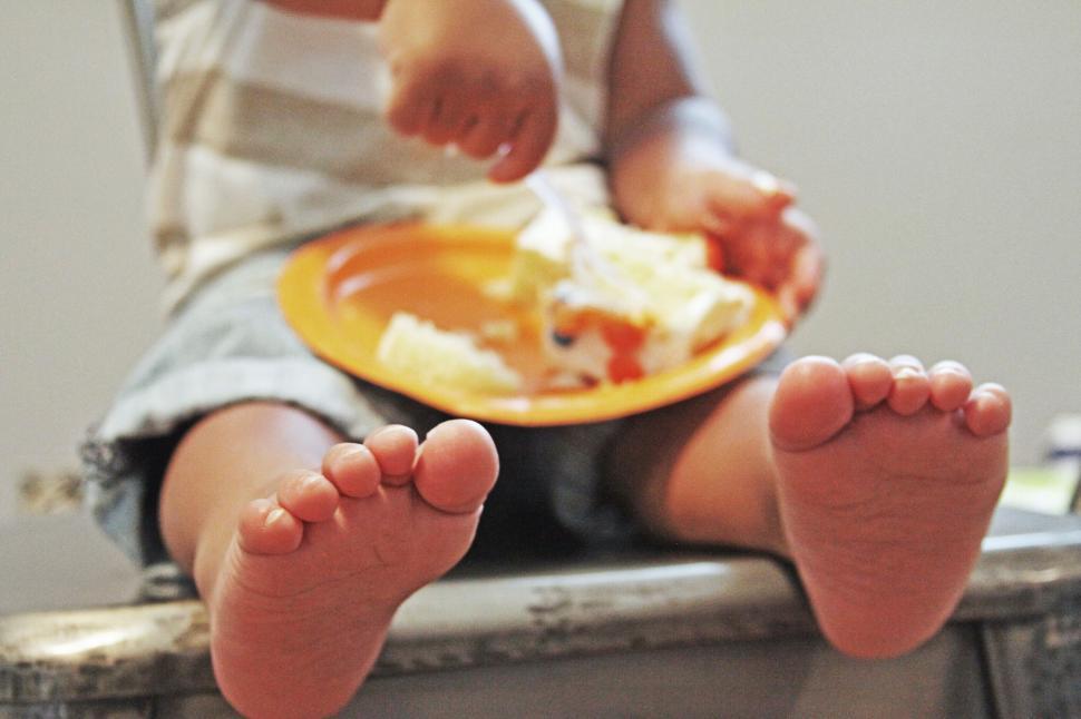 Free Image of Child eating meal with focus on feet 