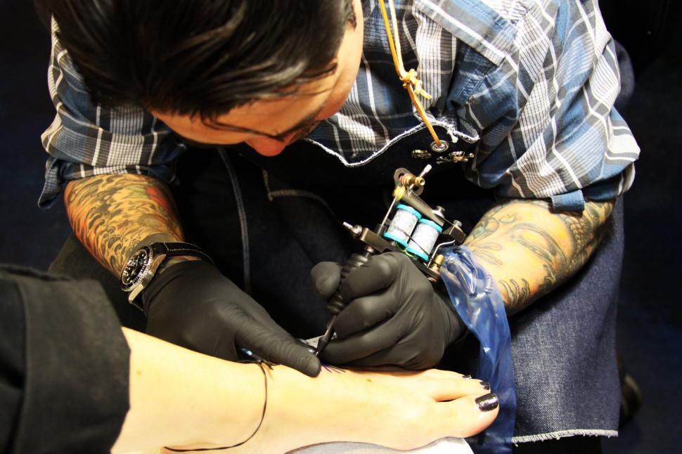 Free Image of Tattoo artist working on a client s arm 