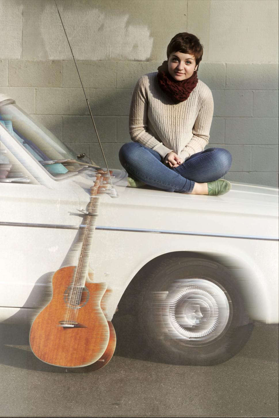 Free Image of Woman sitting with guitar by classic car 