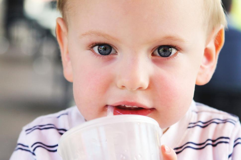 Free Image of Baby drinking from a cup with focused eyes 