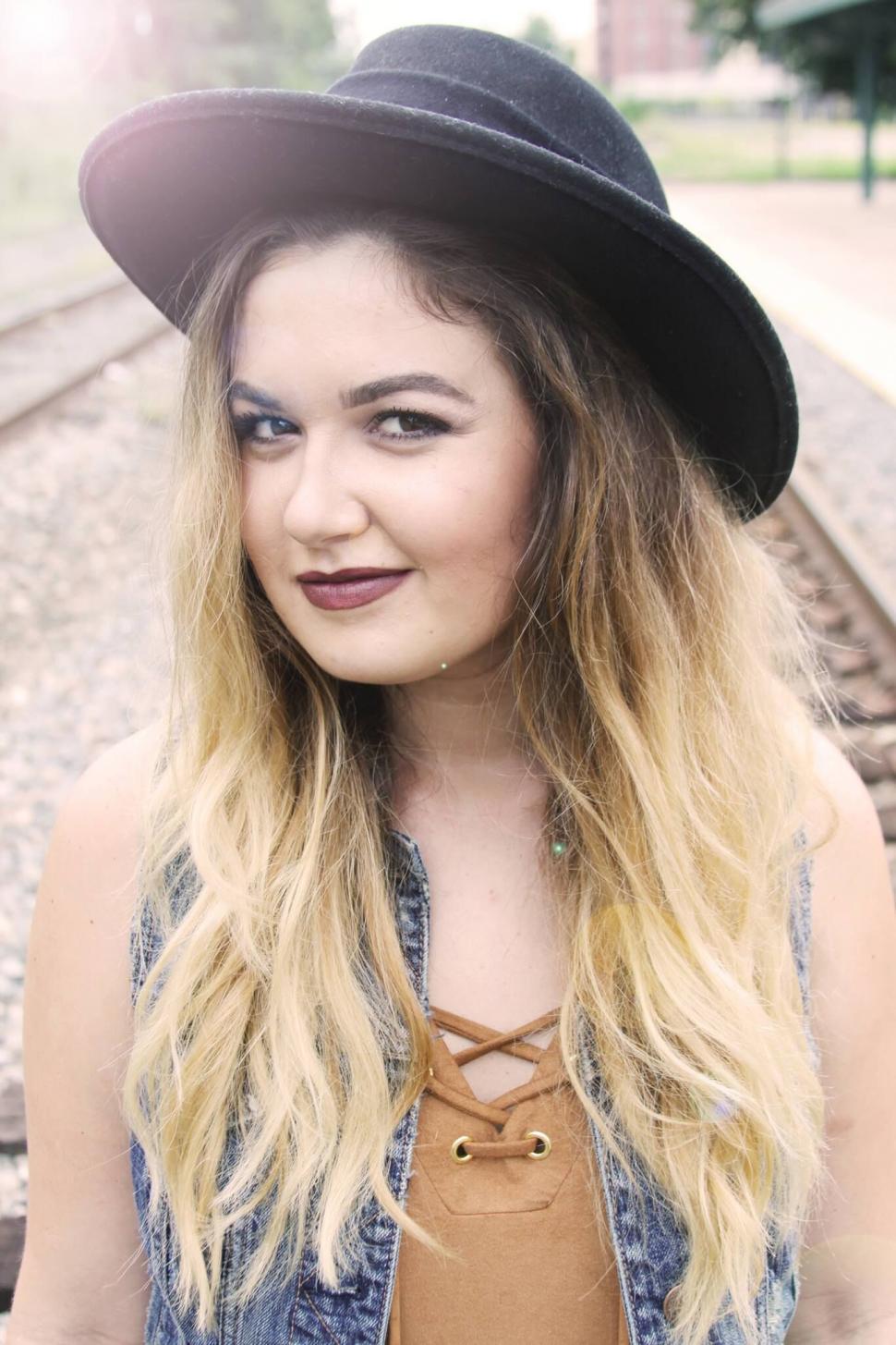Free Image of Young woman in hat on railroad tracks 