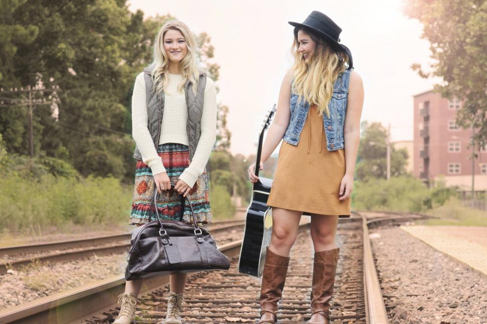 Free Image of Two friends with luggage on train tracks 