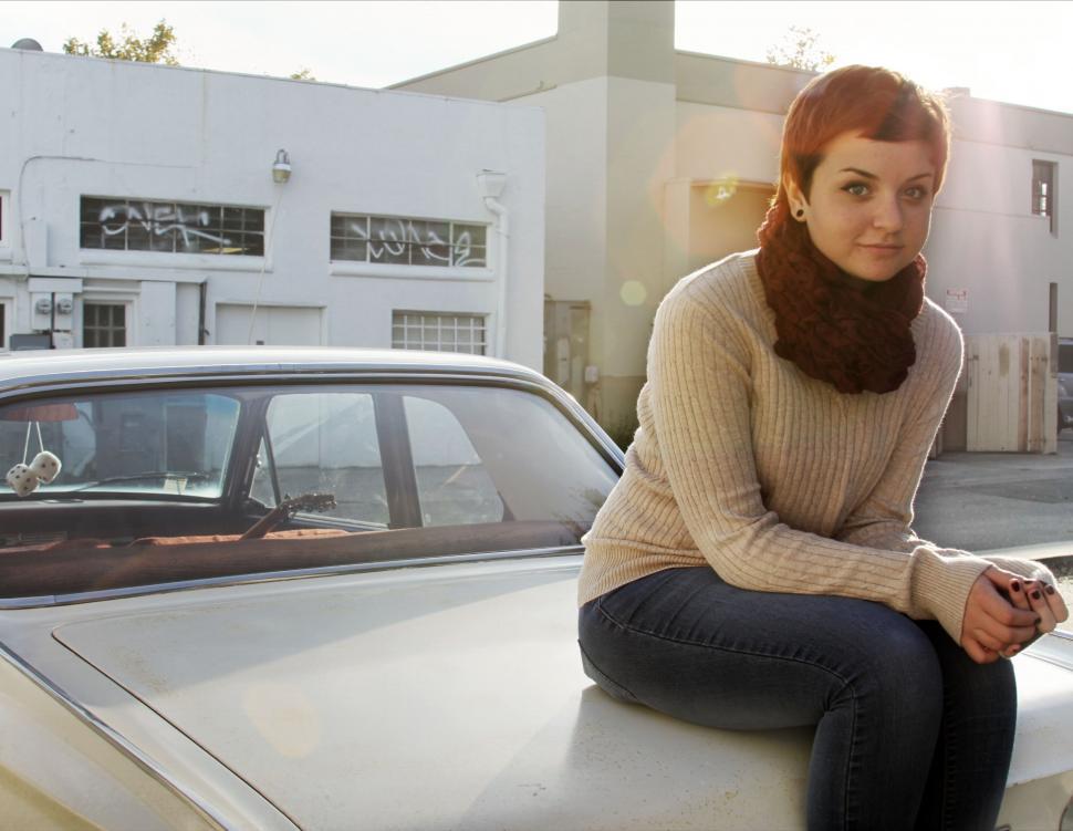 Free Image of Red-haired woman sitting on vintage car 