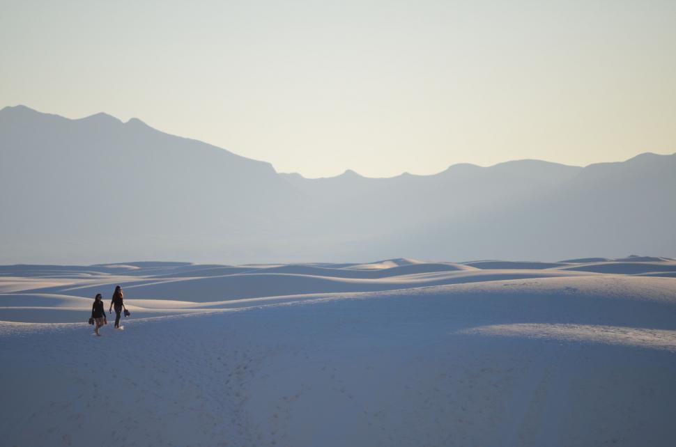 Free Image of Two people walking in a vast desert 