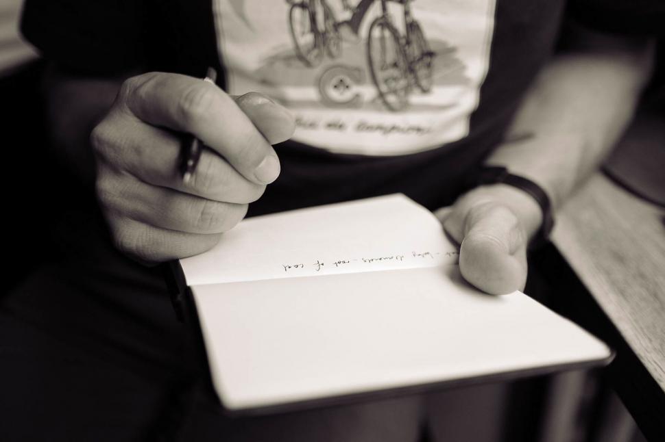 Free Image of Man writing in a notebook with a pen 
