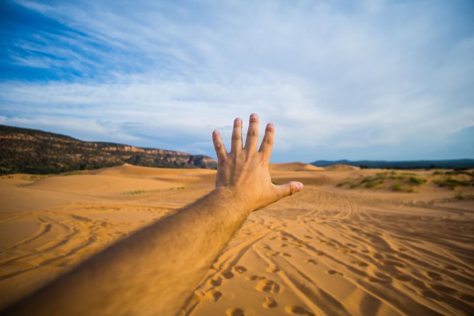 Free Image of Hand reaching out to vast desert landscape 