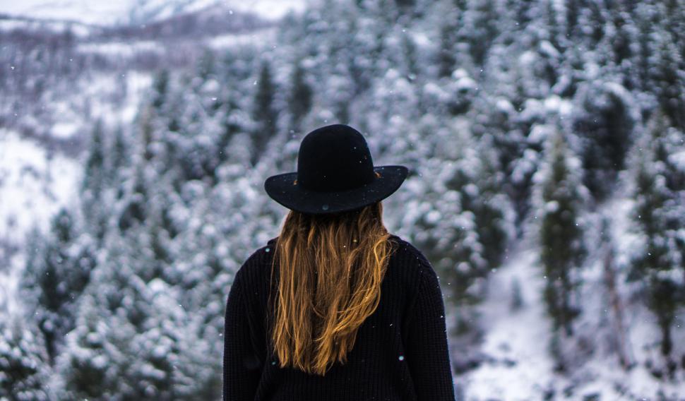 Free Image of Woman in hat looking at snowy forest 