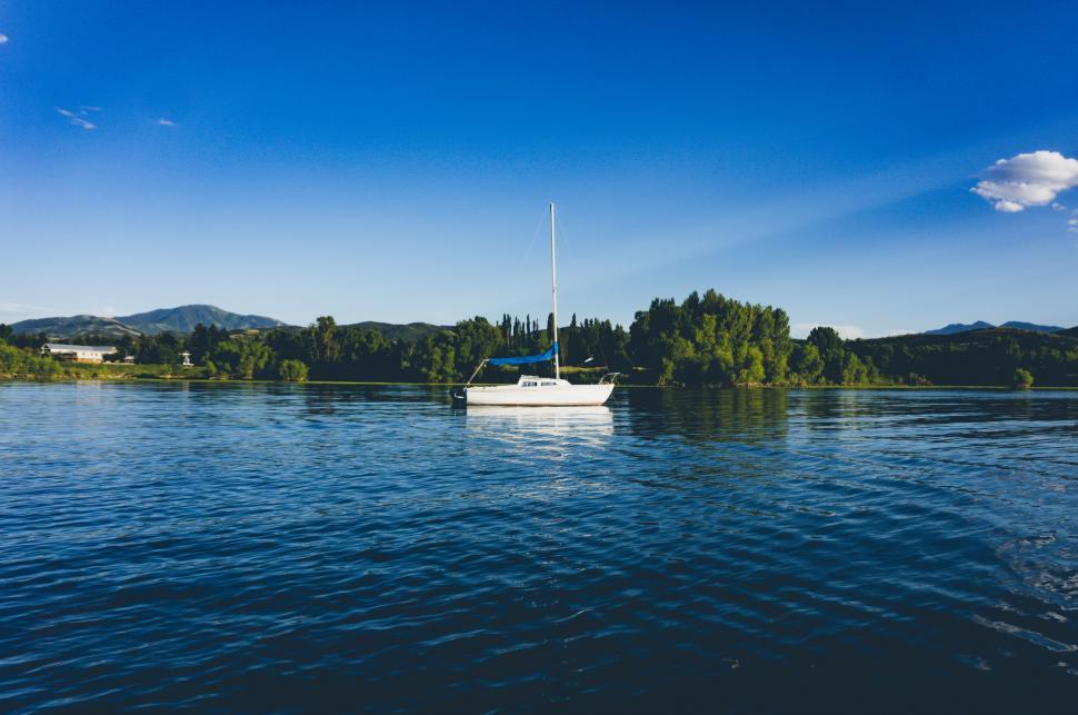 Free Image of Sailboat Floating on Blue Water with Hills 