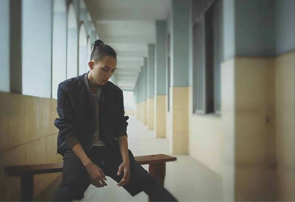 Free Image of Young man sitting in a corridor with face blurred 