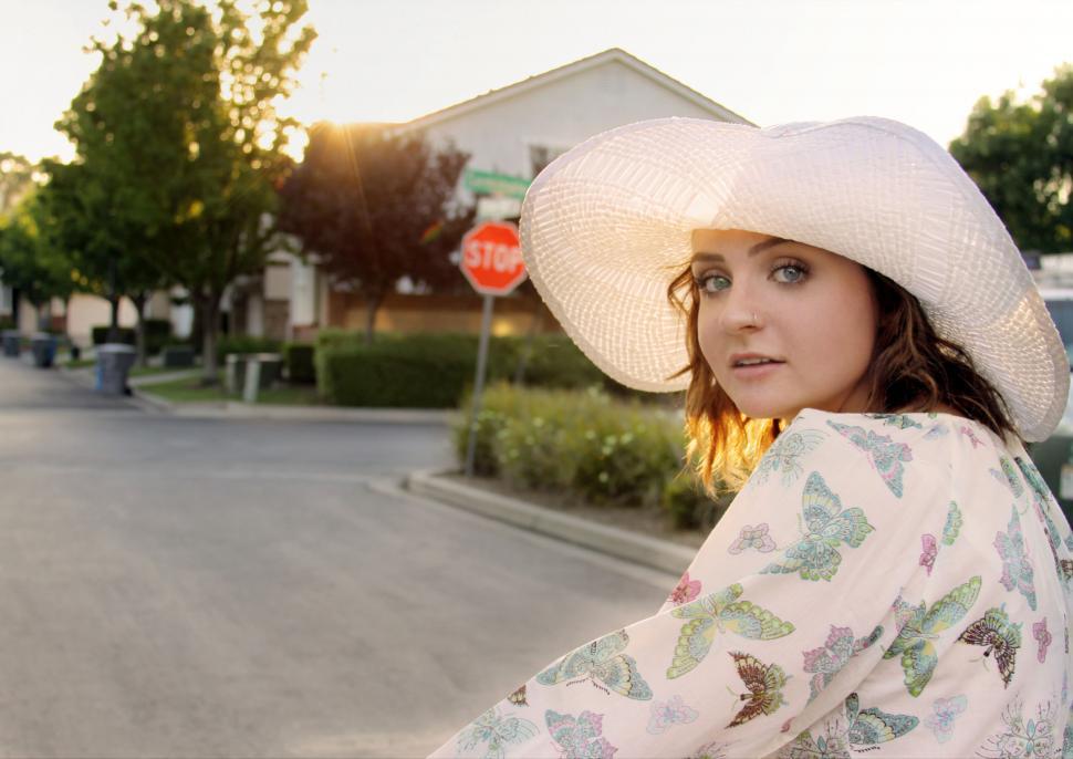 Free Image of Woman in hat looking over shoulder at sunset 