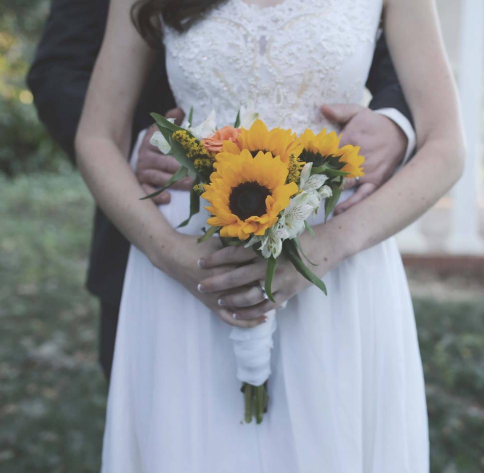 Free Image of Bride and groom holding a sunflower bouquet 