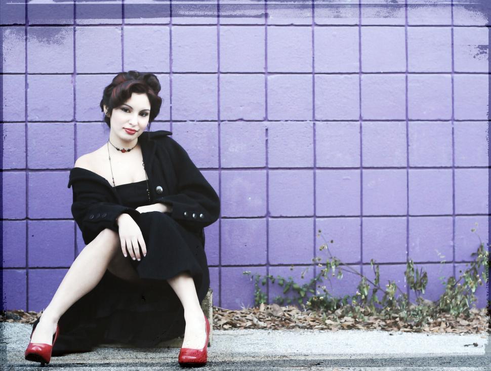 Free Image of Vintage style woman sitting against purple wall 
