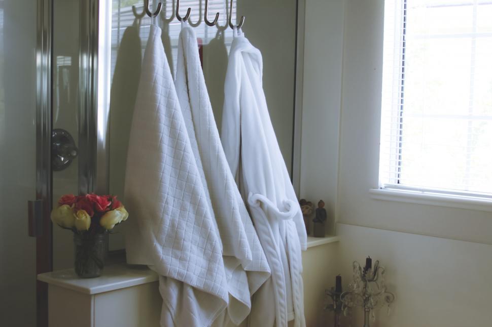 Free Image of Cozy bathroom setting with robes and flowers 