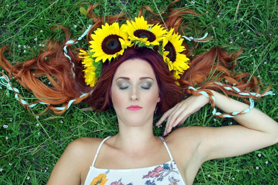 Free Image of Woman lying with sunflower crown in grass 